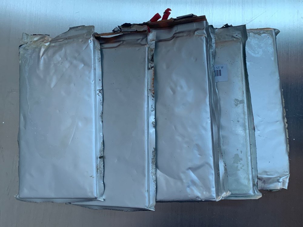 Spent lithium-ion pouch cells laid out on a dark surface before dismantling
